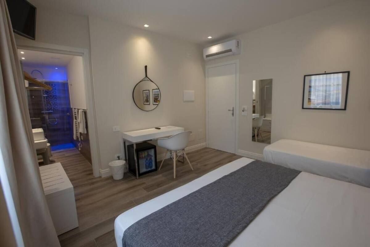 Een moderne hotelkamer met een groot bed, een bureau en een zichtbare badkamer door een geopende deur.