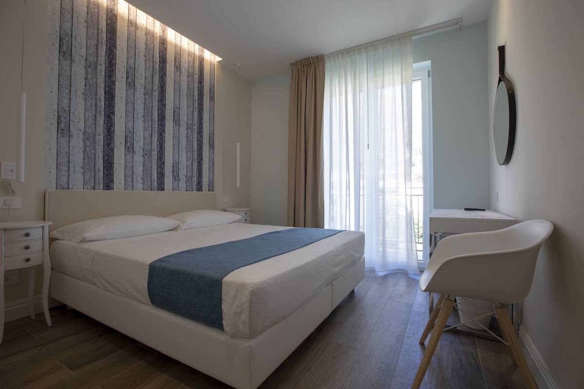 Een moderne slaapkamer met een groot bed, een bureau en een stoel.