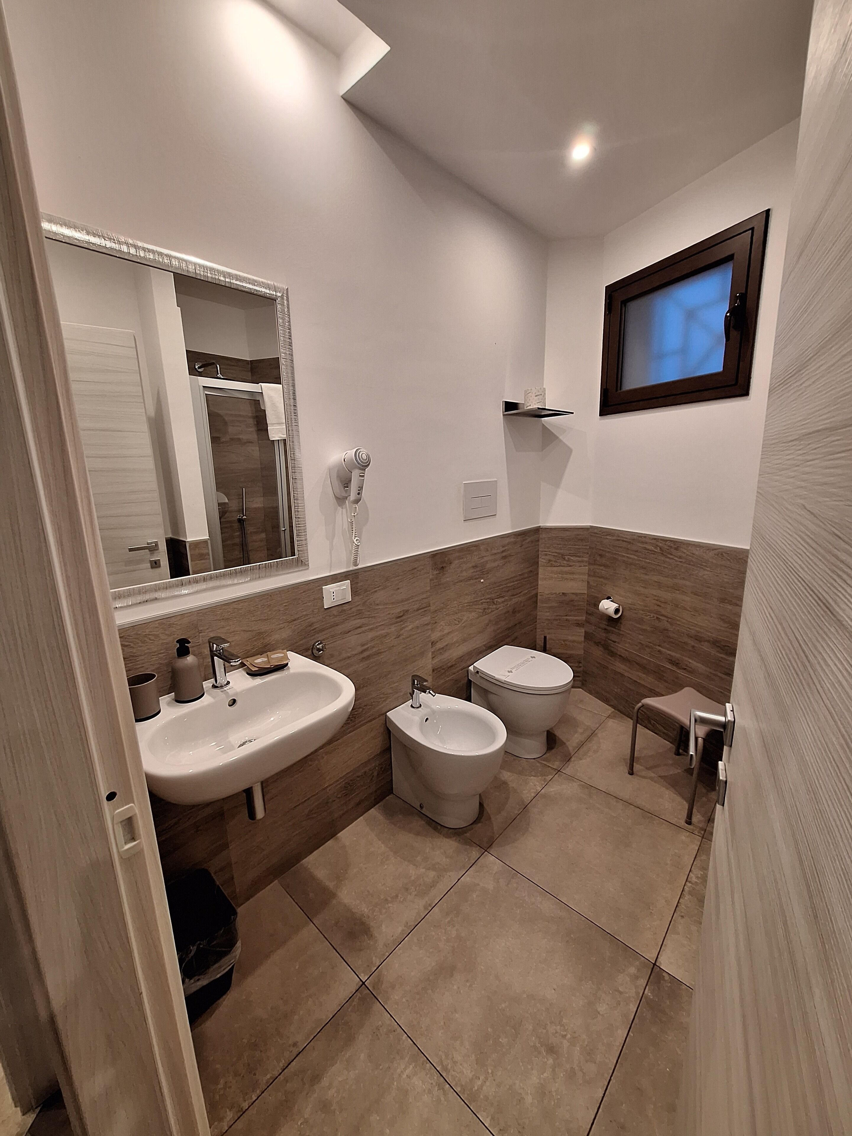 Une salle de bain moderne avec un grand miroir, un lavabo, un bidet et des toilettes.