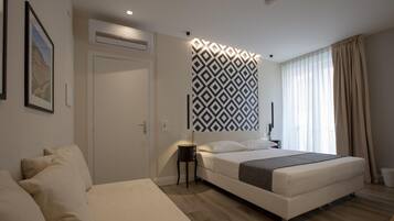 A modern bedroom with a large bed, a bedside table, a wall-mounted air conditioner, and a patterned wall divider.