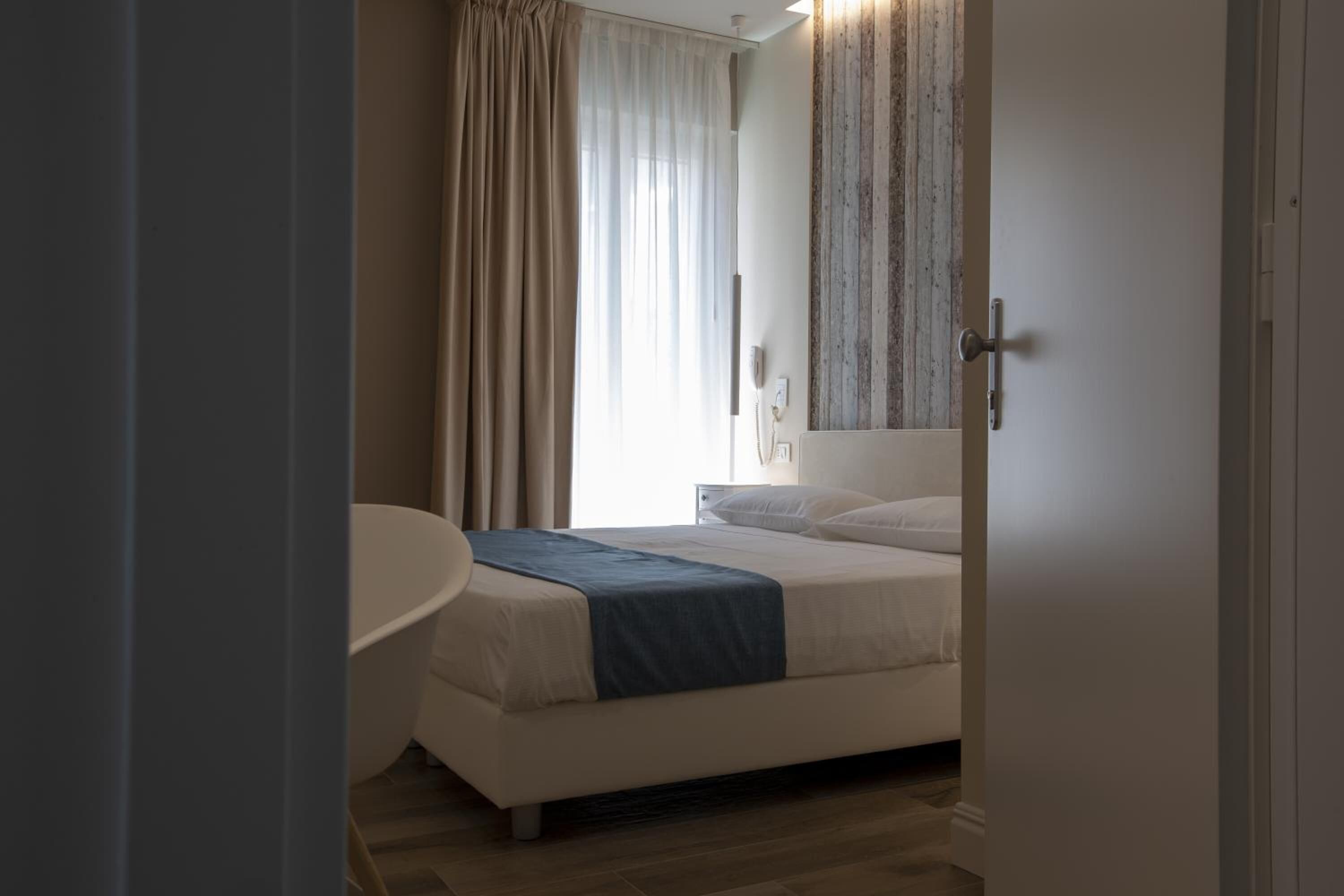 A bedroom with a bed, a bedside table, and a window with curtains.