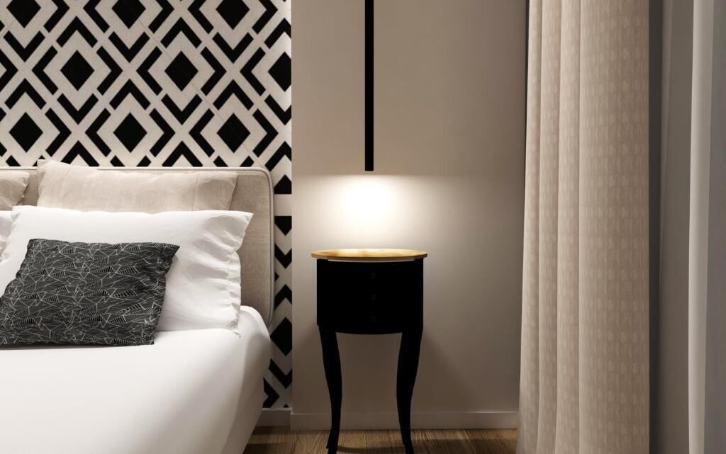 A modern bedroom with a bed, a bedside table, and a geometric-patterned wall.