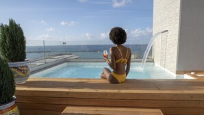 Une personne assise au bord d’une piscine, avec vue sur la mer.