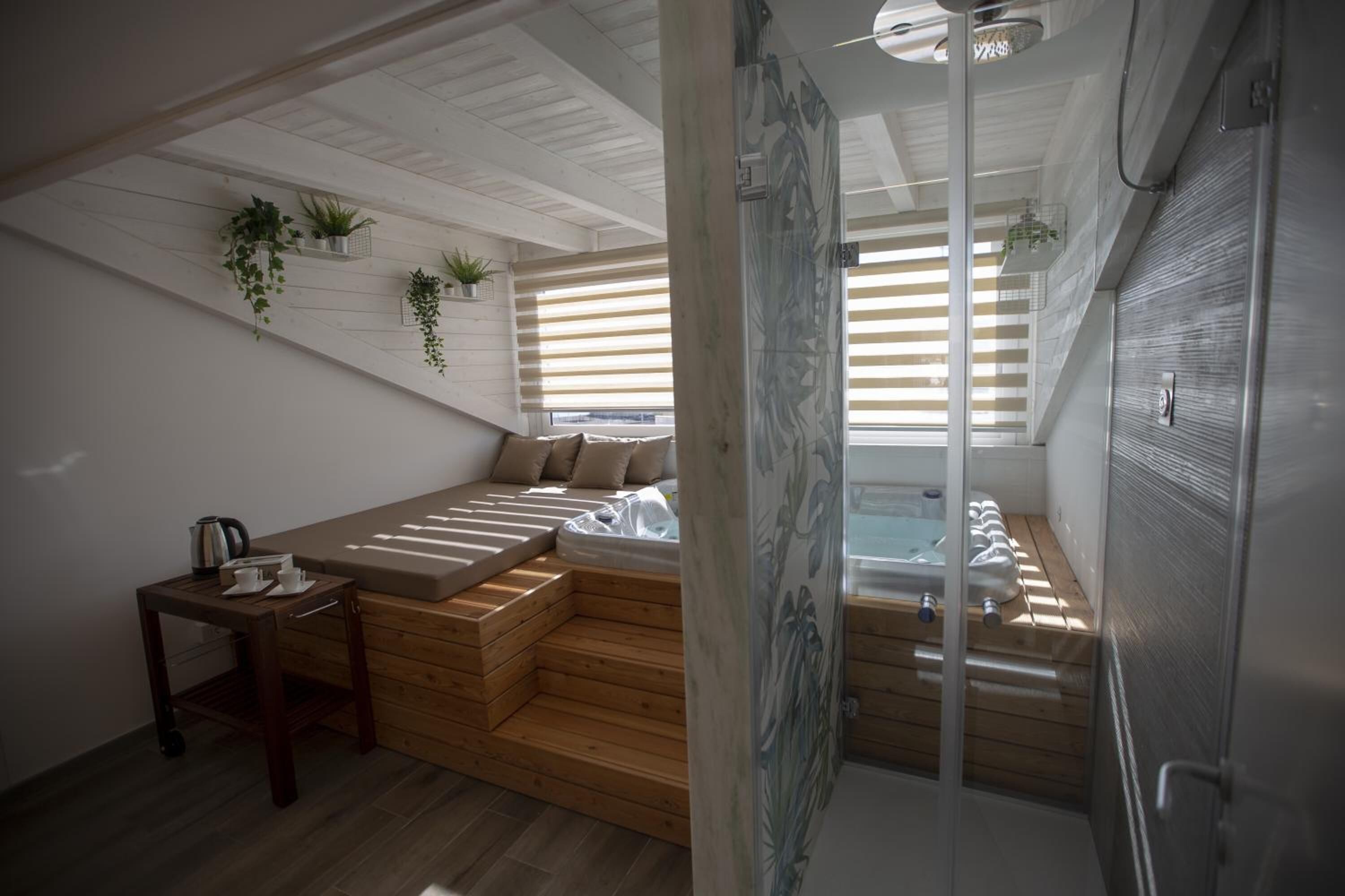 A modern room with a wooden bench, a small table with a kettle, and a glass shower enclosure.