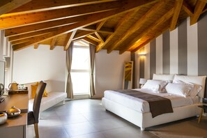 Une chambre avec un grand lit, un bureau avec une chaise, une fenêtre avec des rideaux et un plafond en bois.