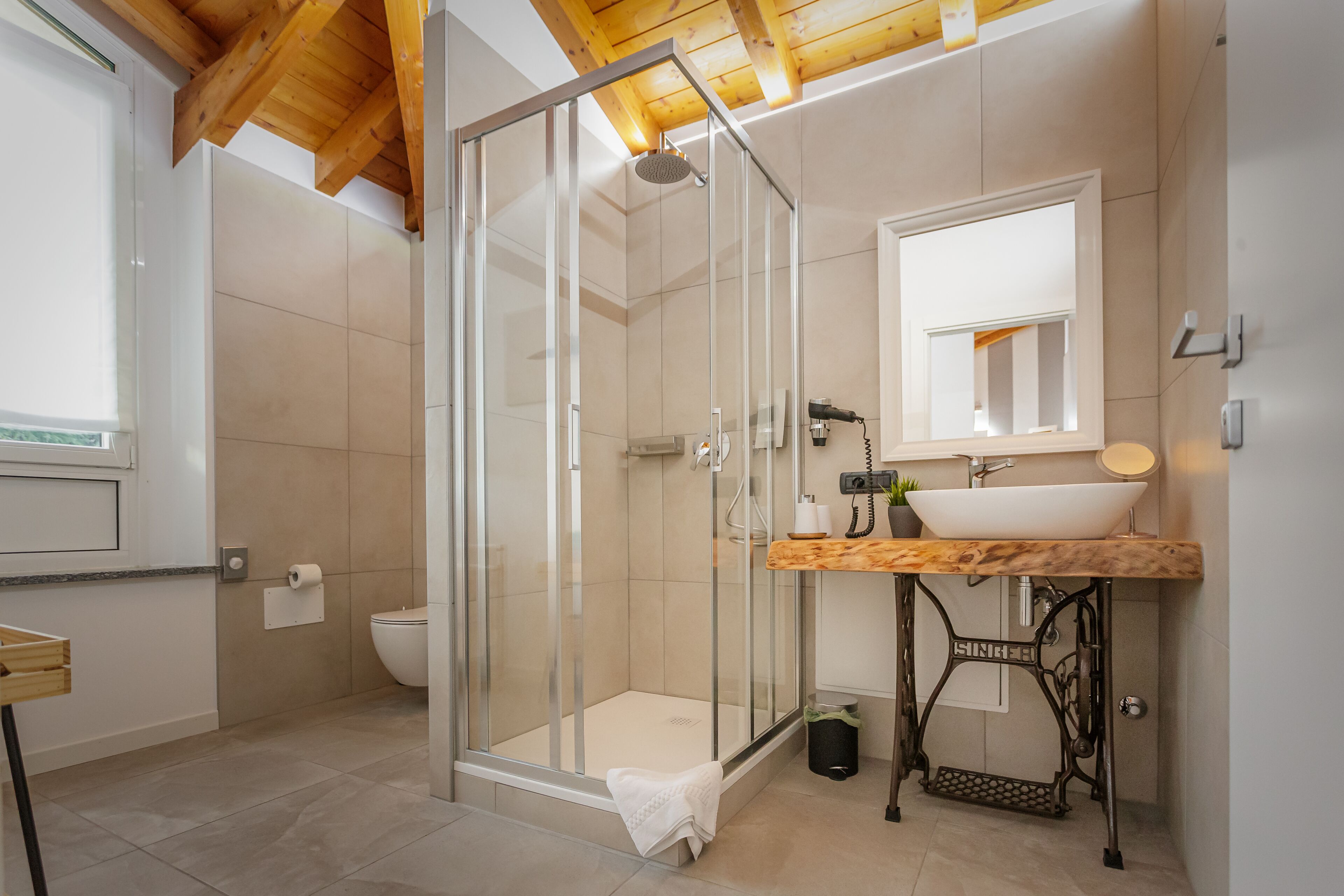 A bathroom with a glass-enclosed shower, a sink with a wooden countertop, and a mirror above the sink.