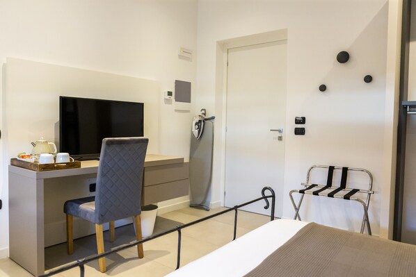Une chambre d’hôtel moderne équipée d’un lit, d’un bureau avec une chaise, d’une télévision et d’un petit coin cuisine.
