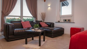 Ein Wohnzimmer mit einem Ledersofa, einem kleinen Tisch mit einer Pflanze und einem roten Schrank.