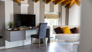 Ein modernes Wohnzimmer mit einem Flachbildfernseher, einem bequemen Sofa mit Kissen, einem Essbereich mit Tisch und Stühlen sowie einem Fenster mit Aussicht.
