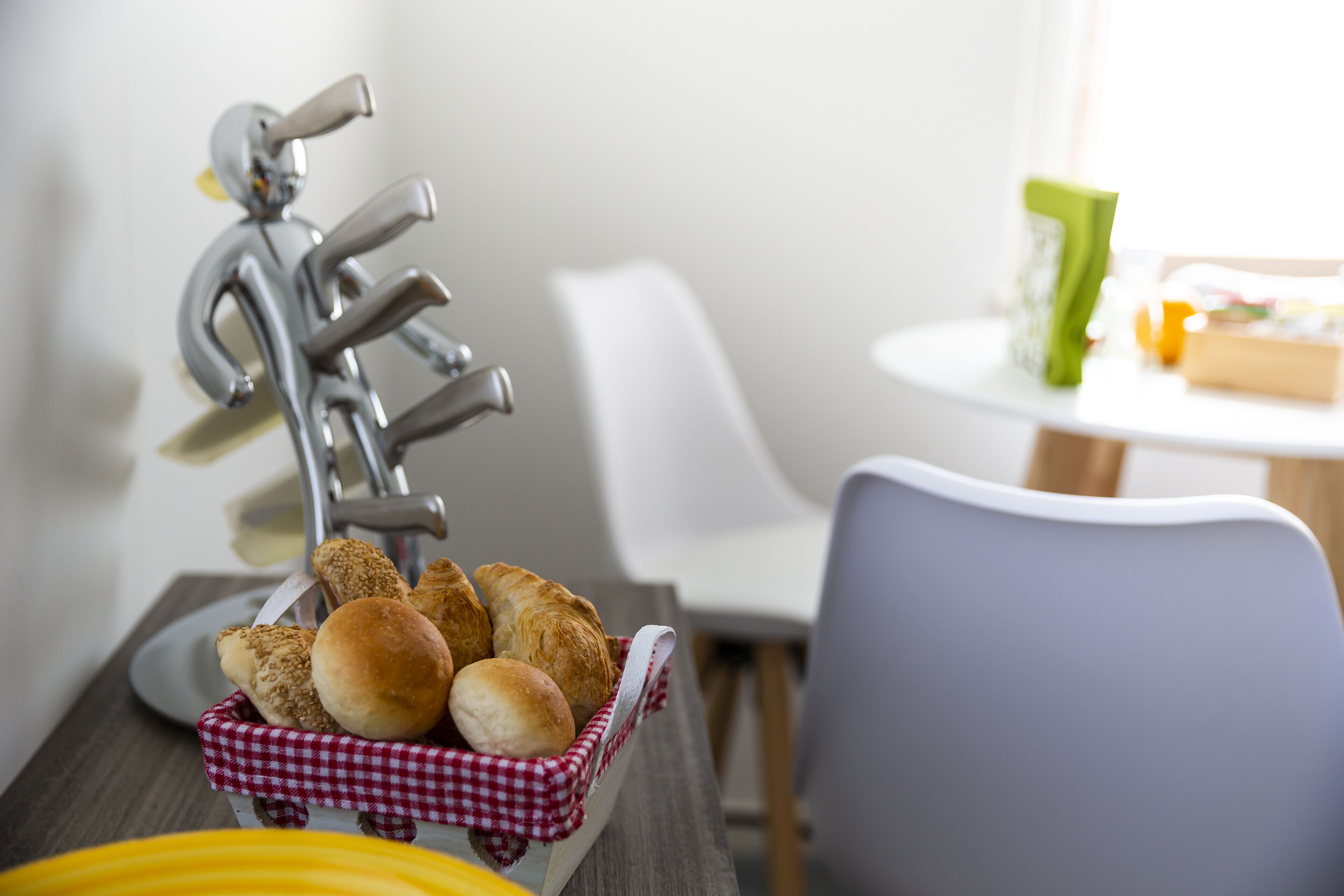 Una colazione con panini in un cesto, una macchina da caffè e una sedia.