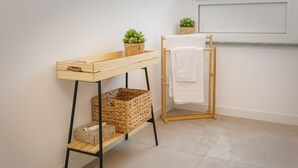 Ein Holztisch mit Körben, einer kleinen Pflanze, einem Handtuchhalter und einem Fliesenboden.