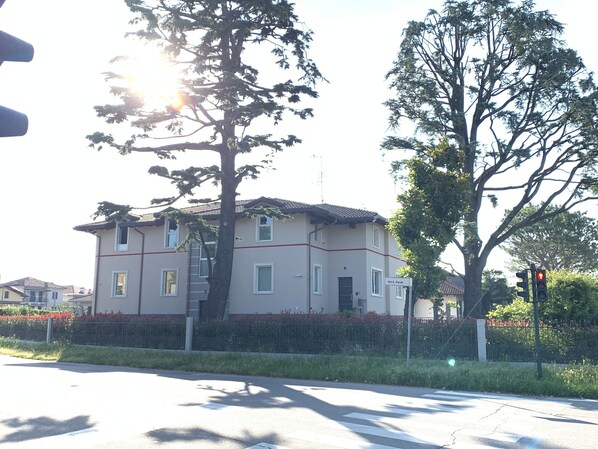 A two-story building with a tiled roof, a visible window, and a sign that reads "Via E. Fermi". - Casa Ananda (Ferno)