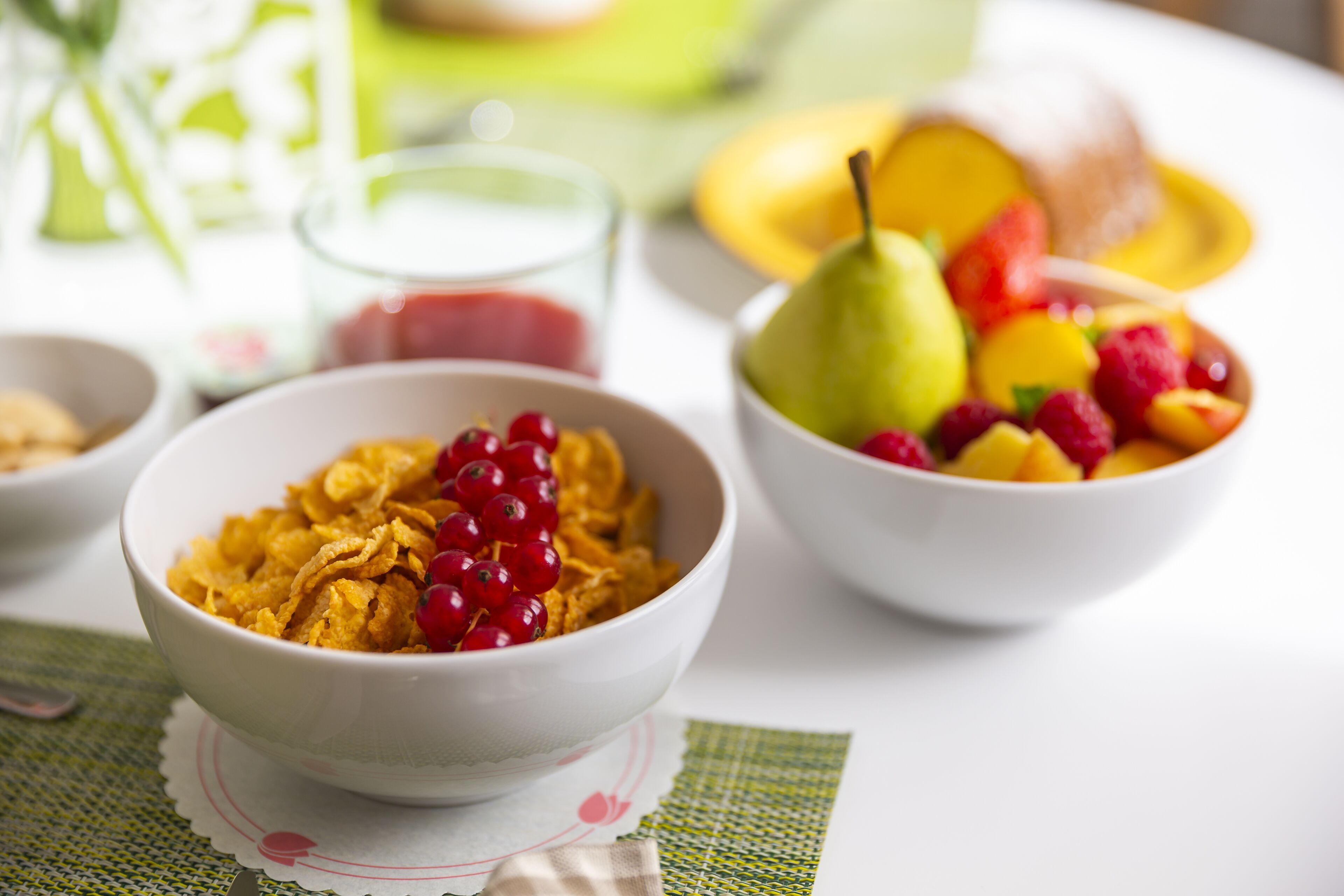 Une table mise pour le petit-déjeuner avec des bols de céréales et des fruits.