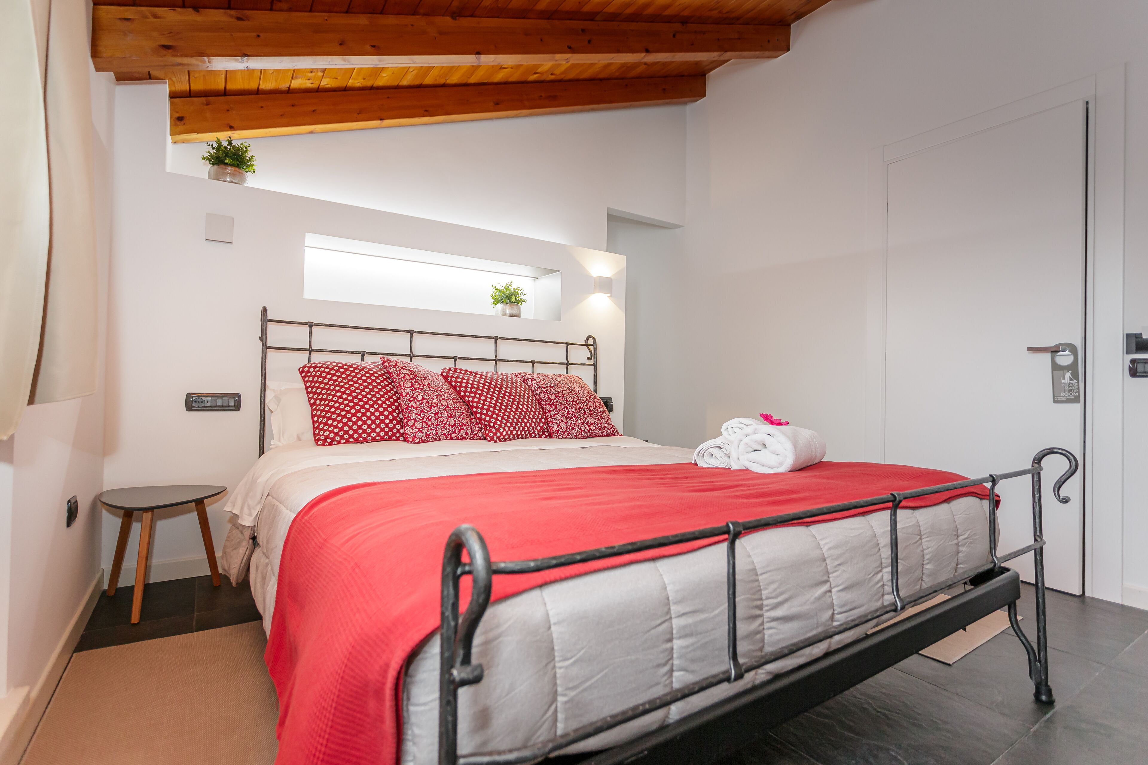 Une chambre à coucher avec un lit, une petite table, une fenêtre et une porte.