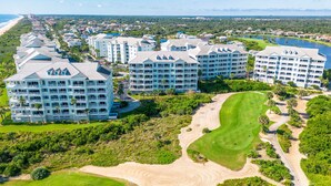 Un resort con varios edificios de gran altura, un campo de golf y una playa al fondo.