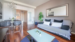 Ein modernes Wohnzimmer mit einer Couch, einem Couchtisch und einem Essbereich mit Stühlen und einer Chandeliebre.