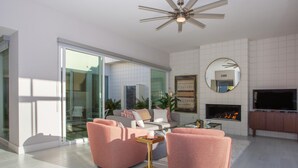 Una sala de estar moderna con chimenea, televisor de pantalla plana y ventilador de techo.