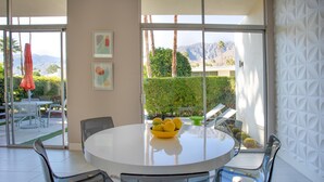 Un comedor moderno con una mesa redonda, sillas transparentes y un cuenco de limones.
