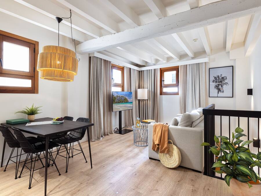 Una sala de estar moderna con comedor, vigas de madera, televisor y sofá.