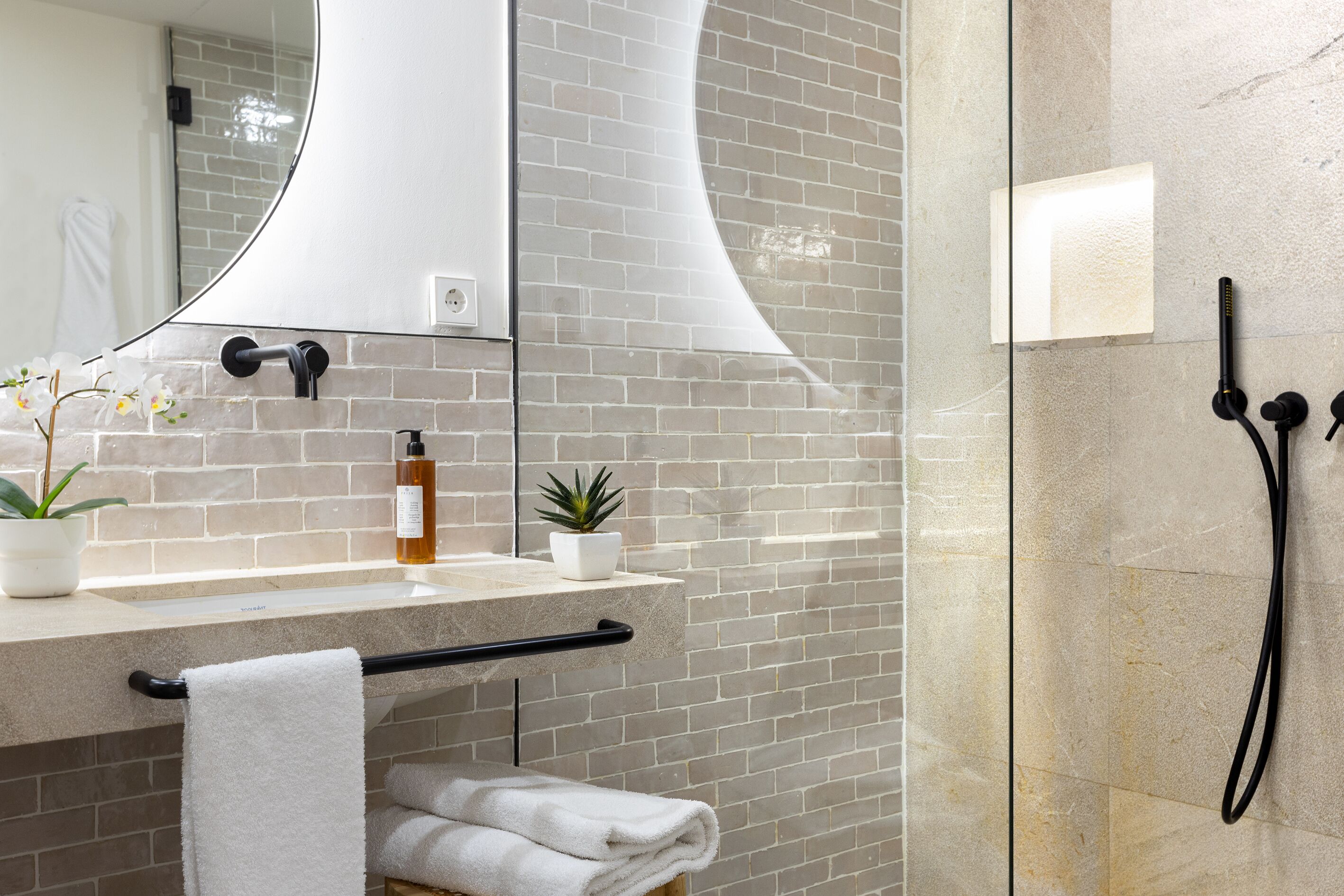 A modern bathroom with a large mirror, a sink with a towel rack, and a shower area.
