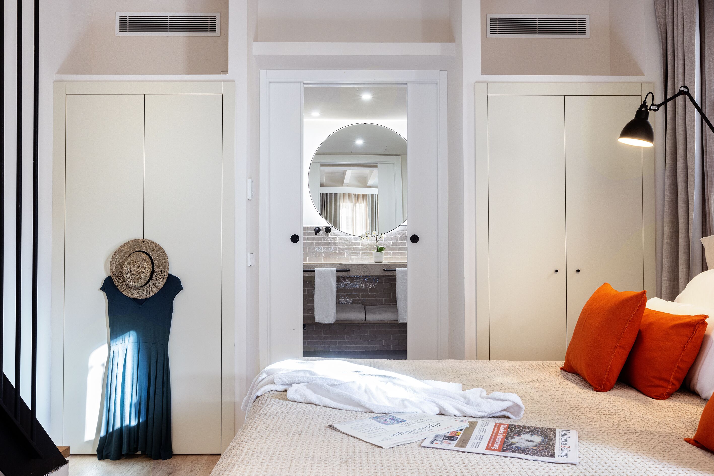 Un dormitorio con cama, mesita de noche, espejo y armario.