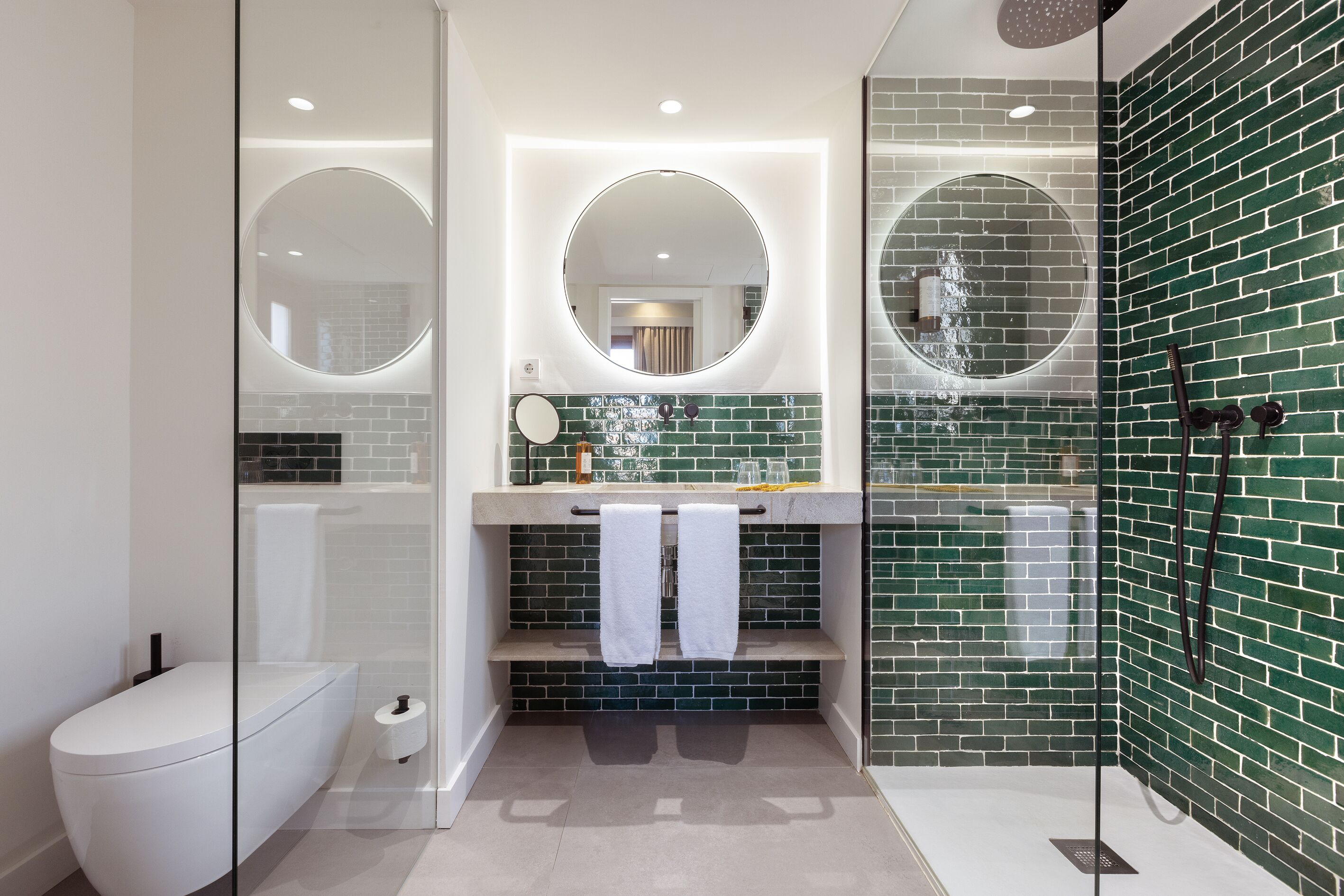 Un bany modern amb vàter, dutxa amb envàs de vidre i un lavabo amb mirall.
