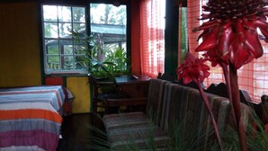 Una habitación con cama, sofá, escritorio y ventana con vista a árboles.