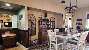 A dining area with a wooden table, white chairs, and a floral rug.