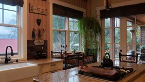 A kitchen with a sink, stove, and a large window with a view of the outdoors.