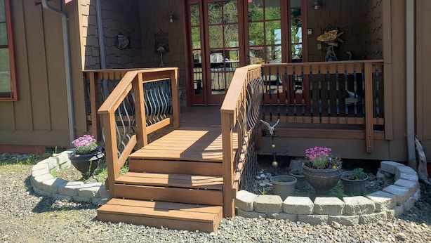 A wooden house with a porch, a wooden staircase, and a railing.