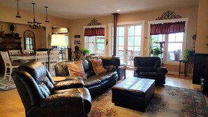 A living room with leather sofas, a coffee table, and a dining area with a chandelier.
