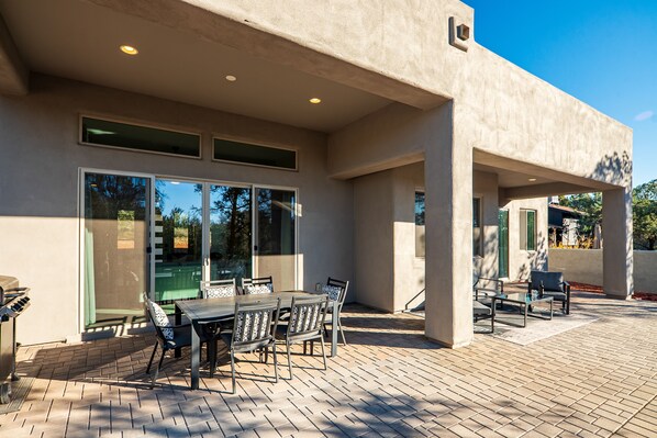 A patio area with a table and chairs, a grill, and a covered seating area.
