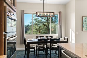 Un espace repas avec une grande fenêtre, un lustre et un comptoir de cuisine.