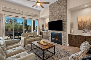 A spacious living room with a fireplace, a large TV, and a comfortable seating area.
