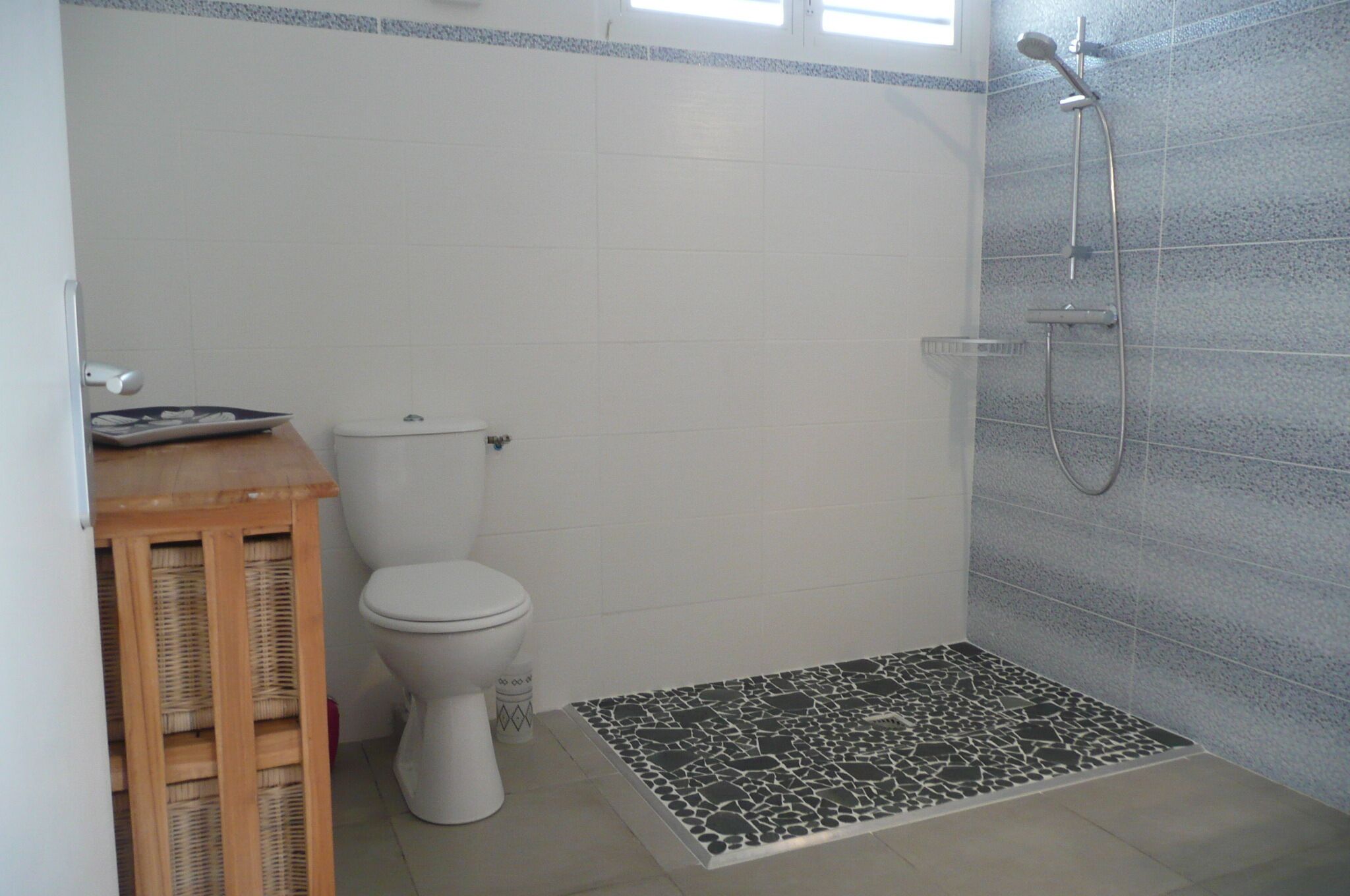 Ein Badezimmer mit Toilette, Dusche und einem kleinen hölzernen Hocker.