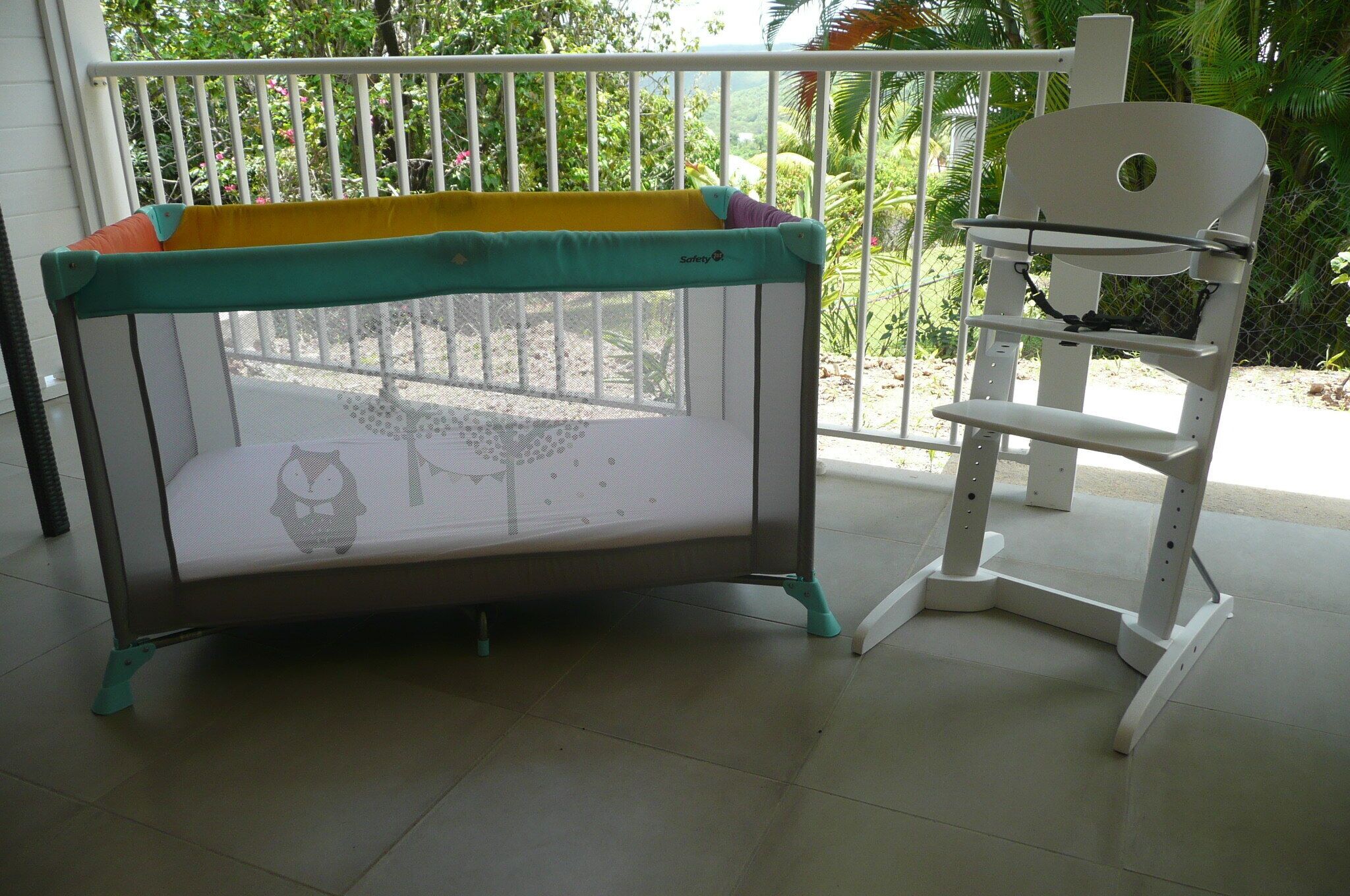 A baby playpen with a safety gate and a high chair.