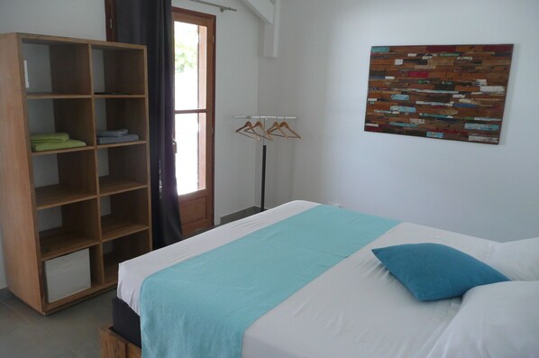 A bedroom with a bed, a wooden wardrobe, and a wall-mounted coat rack.
