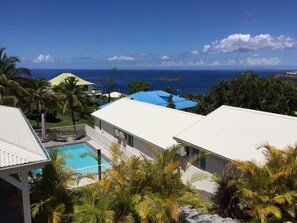 A residential area with a swimming pool, white houses, and a view of the ocean.