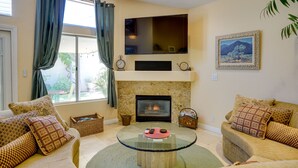 A living room with a fireplace, two sofas, a coffee table, and a TV mounted above the fireplace.