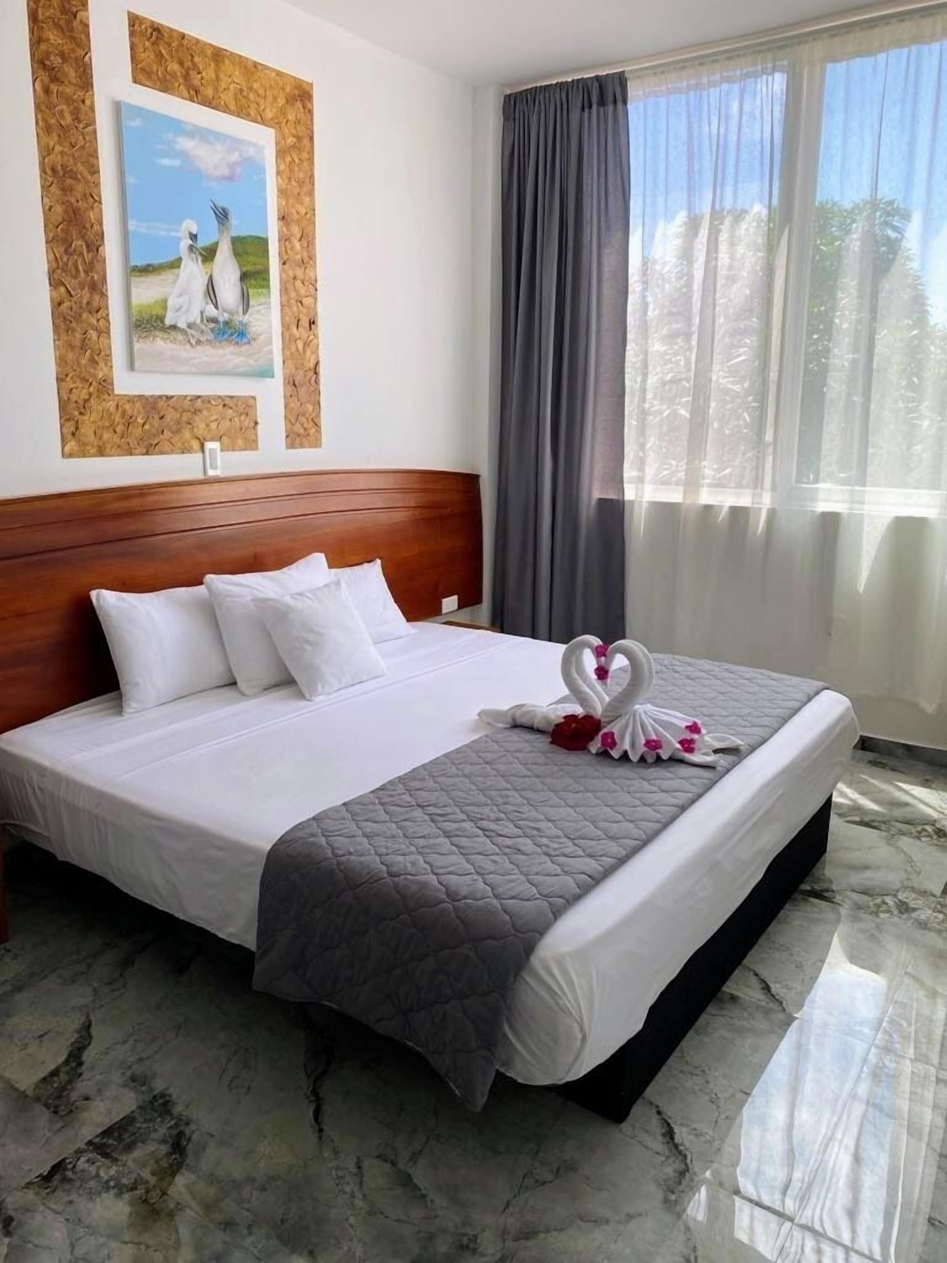 A neatly made bed with a quilted blanket, a wooden headboard, and a painting on the wall.