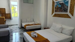 Una habitación de hotel con dos camas, un ventanal grande, un cuadro en la pared y un armario de madera.