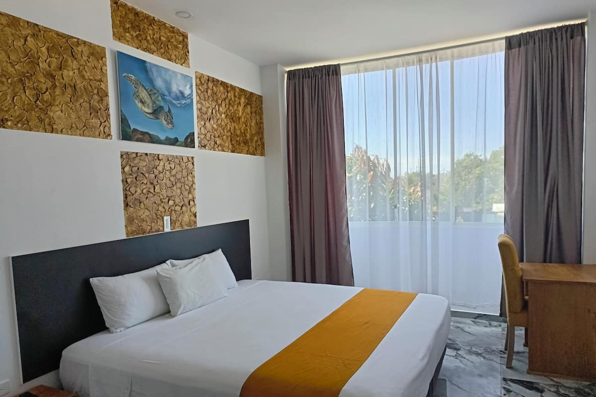 Ein Hotelzimmer mit einem großen Bett, einem Schreibtisch und Blick ins Freie.