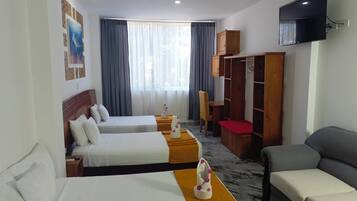 A hotel room with two beds, a sofa, a TV, a wardrobe, and a desk.