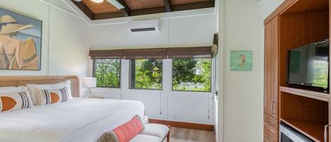 A bedroom with a large bed, a bench, a ceiling fan, and a TV.
