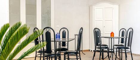 A dining area with a table and chairs, a potted plant, and a white cabinet.