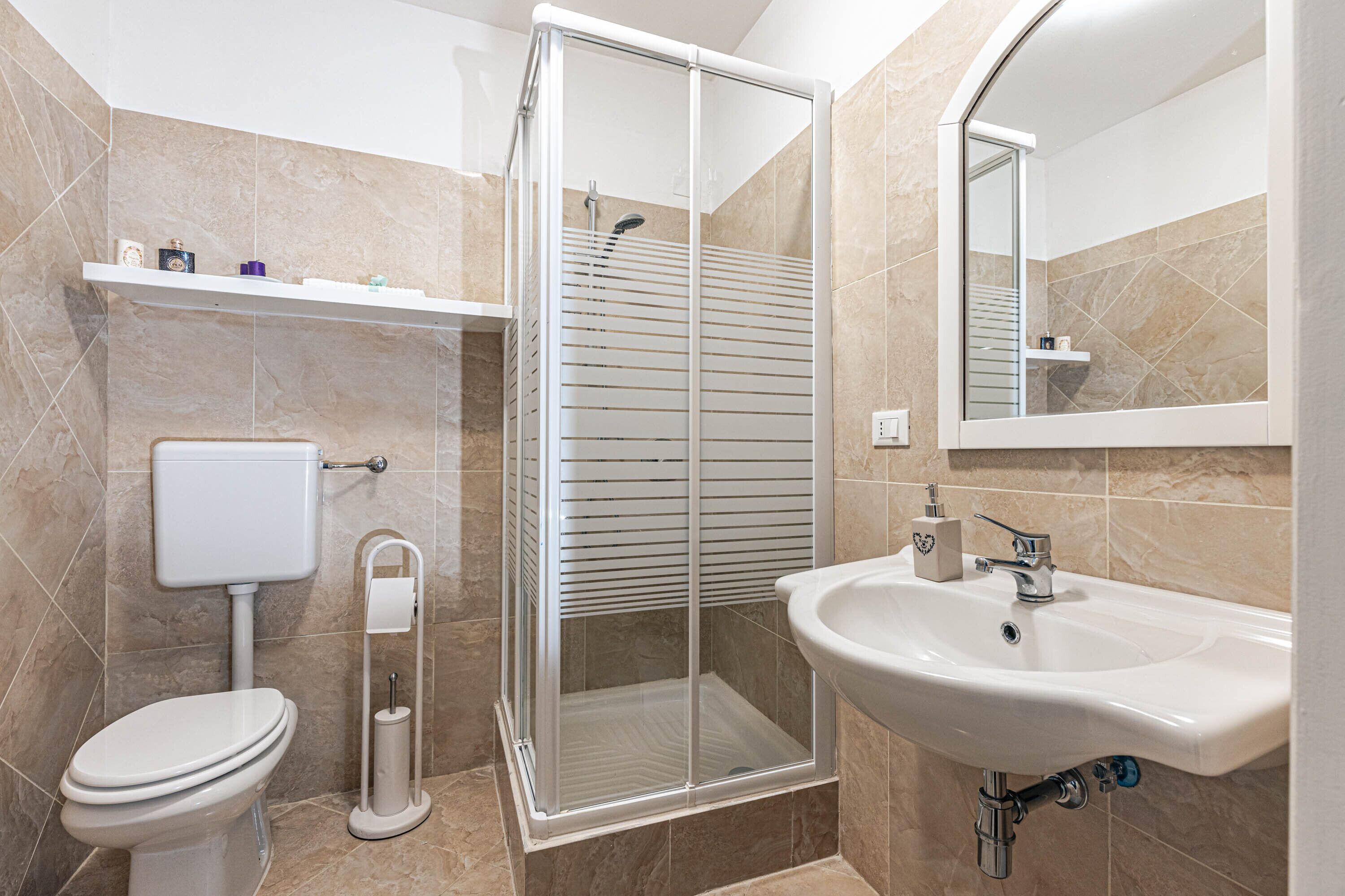 Ein Badezimmer mit Toilette, einer Duschkabine und einem Waschbecken.
