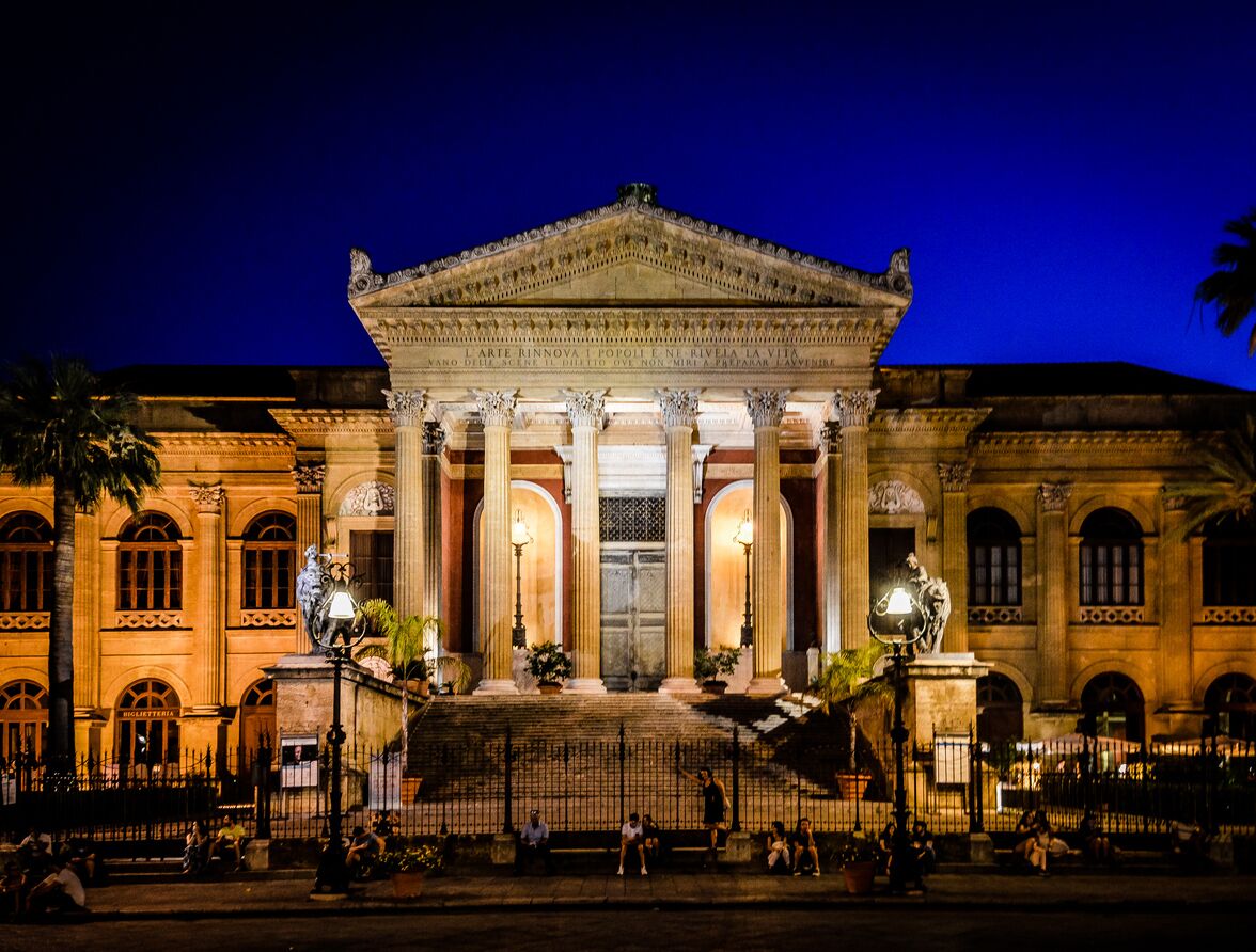 A classical building with a central entrance, columns, and steps leading up to it.