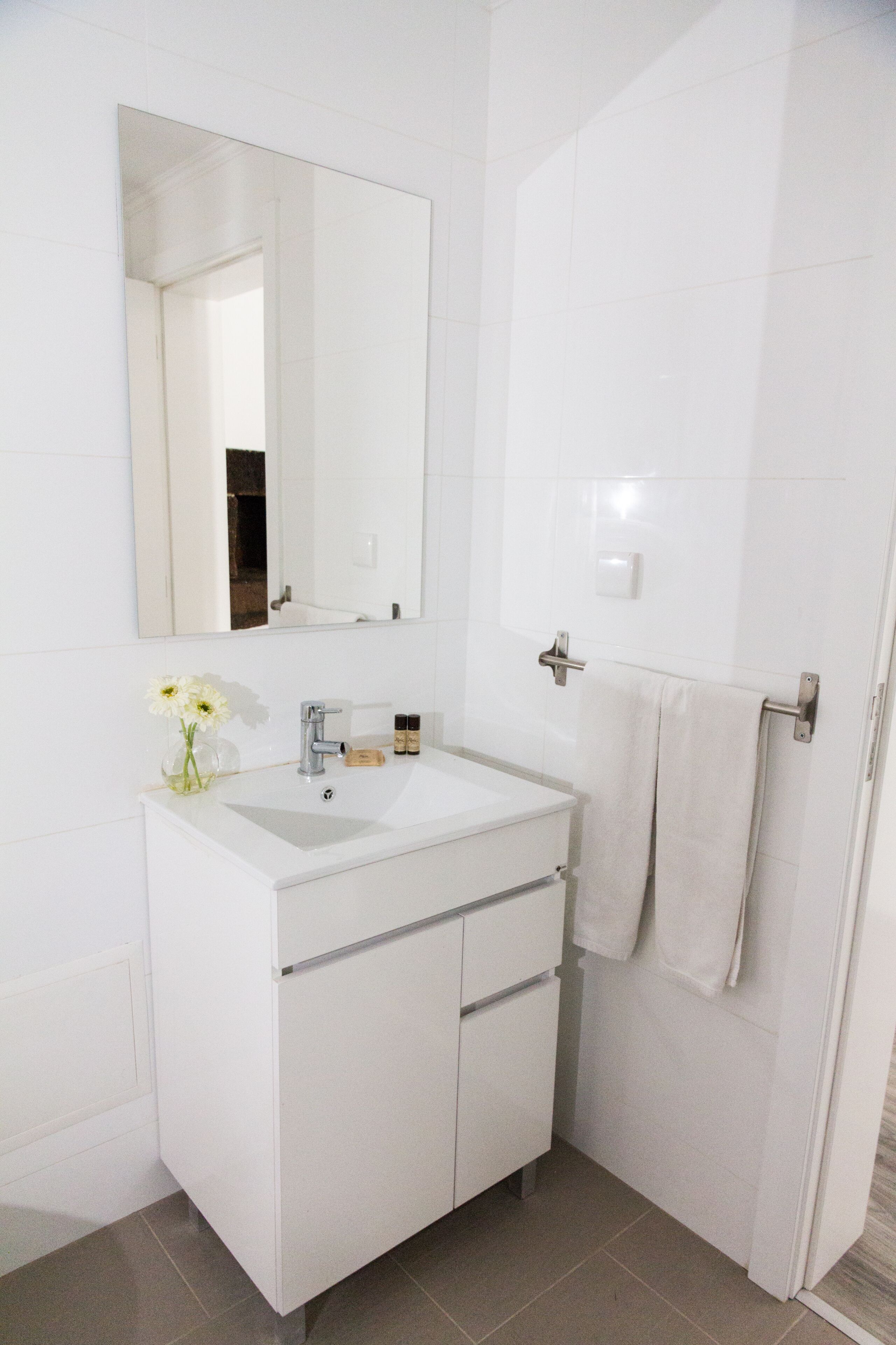Ein helles Badezimmer mit Waschbecken, Spiegel und Handtuchhalter.
