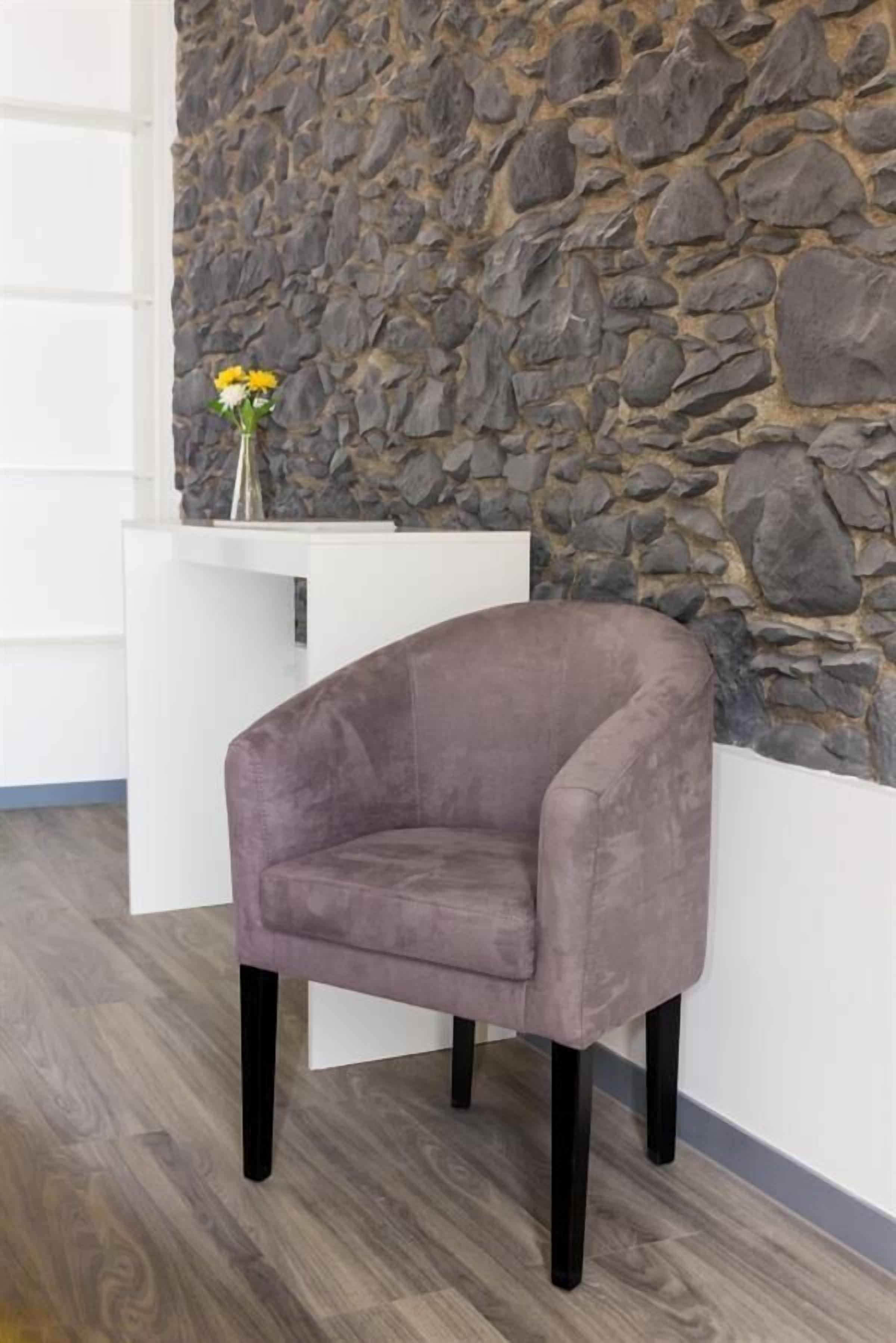A room with a stone wall, a white reception desk, and a purple armchair.