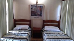 Una habitación con dos camas individuales, un cuadro en la pared y una mesita entre las camas.